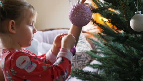 A-child-adds-an-ornament-to-a-Christmas-tree-to-decorate-for-the-holidays