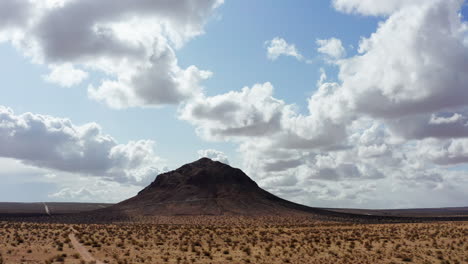 A-black-rocky-mountain-in-the-middle-of-the-Mojave-desert-on-a-bright-sunny-day---Wide-shot