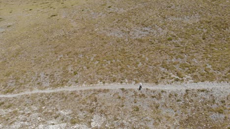 AERIAL-shot-of-a-man-walking-,-hiking-alone-at-Kissavos-Greek-mountain-at-Thessaly-region-,-drone-view,-route-at-mountain-,-sport-life-style-,-healthy-way-of-leaving-brown-landscape