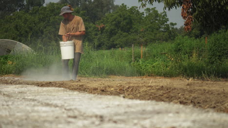 Front-view-of-a-farmer-adding-fertilizer-to-the-soil-while-preparing-the-plantation-field-for-cultivation