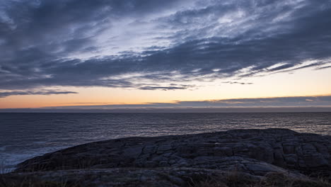 Time-lapse-shot-of-clouds-moving-above-a-rocky-coast-and-the-Skagerrak-sea,-at-dusk,-on-Justoya-island,-in-Aust-Agder,-Norway