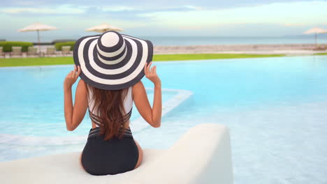 An-attractive-woman-relaxing-by-a-swimming-pool-at-a-luxury-hotel-resort