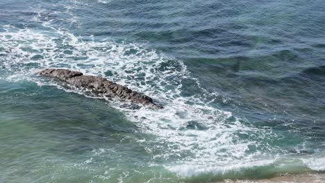Kleine-Wellen,-Die-Auf-Einigen-Felsen-Am-Strand-Von-Poça-In-Estoril-Krachen
