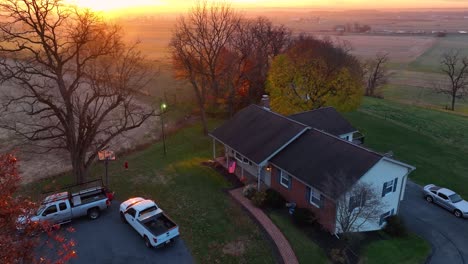 Aerial-establishing-shot-of-one-story-home-in-USA-with-American-flag-at-beautiful-colorful-sunrise