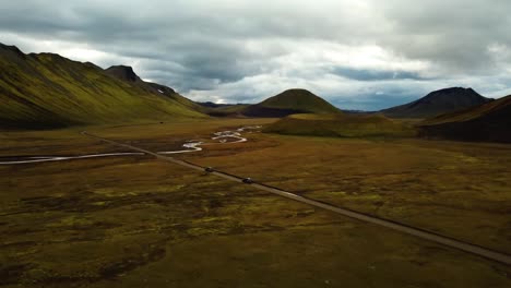 Aerial-landscape-view-over-two-cars-speeding-on-a-dirt-road-through-icelandic-highlands