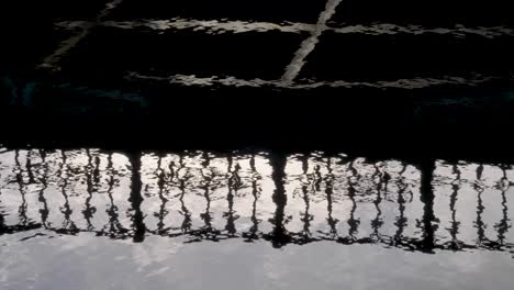 Close-up-water-surface-reflection-promenade-steel-guards,-silhouette-on-river
