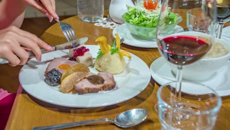 Close-up-decorative-dinner-on-plate-with-red-wine-at-restaurant,-Female-hand-hold-fork-and-knife,-Static-shot