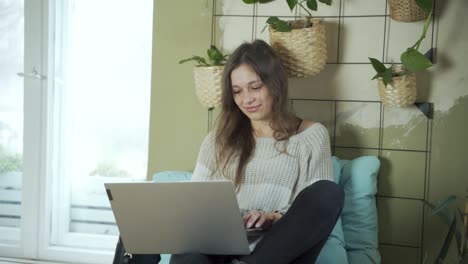 Dark-hair-female-European-student-is-working-on-her-modern-laptop-wearing-winter-clothes