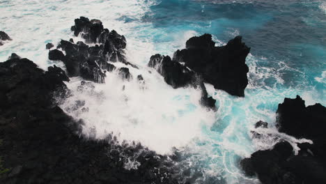 Toma-Aérea-En-Cámara-Lenta-De-Una-Poderosa-Ola-Rompiendo-Sobre-Rocas-De-Lava-Irregulares-En-Hawaii