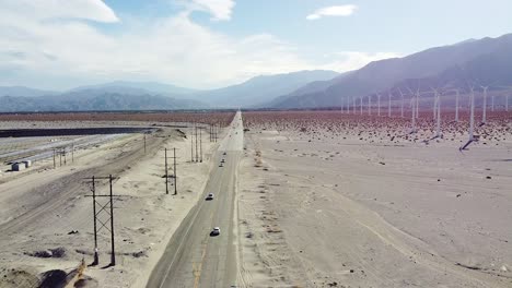 Endless-American-highway-and-massive-wind-turbine-farm-on-desert-area,-aerial-drone-view