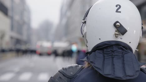 Female-police-officer-against-blue-flashing-lights-in-the-background-during-riots---POV-shot-over-shoulder