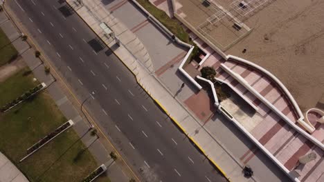 Aerial-top-down-shot-of-Man-running-on-walkway-beside-exotic-beach-during-sunny-day-in-summer---Mar-del-Plata-City,Argentina