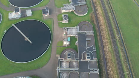 Aerial-of-Waste-water-flowing-through-aeration-tank-at-sewage-water-treatment-plant---drone-flying-back-and-revealing-industrial-site