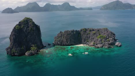 Aerial-drone-circling-around-huge-limestone-cliffs,-turquoise-water-and-natural-archipelago-paradise-in-El-Nido,-Palawan,-Philippines