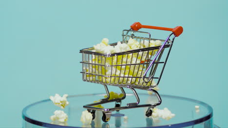 Shopping-kart-filled-with-popcorn-in-slow-motion-with-baby-blue-background