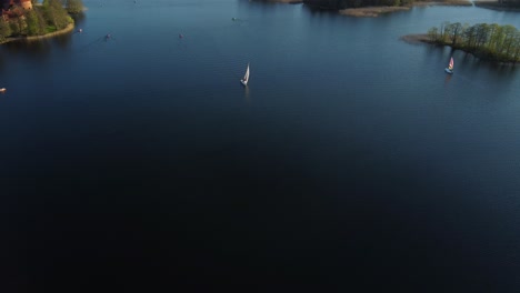 yacht-sailing-alongside-Trakai-island-castle-on-Lake-Galve,-Lithuania