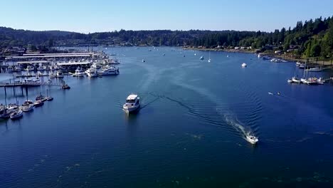 Aerial,-reverse,-drone-shot-following-boats-leaving-Gig-Harbor,-on-a-sunny-day,-in-Washington,-USA