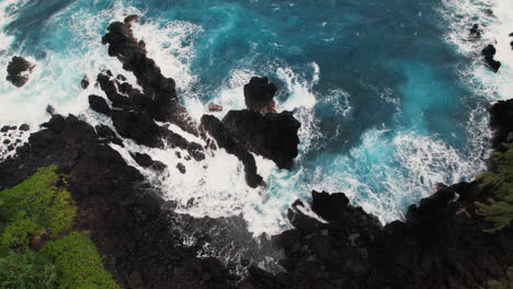 Aerial-view-of-rocky-cove-with-waves-crashing-around-dark-rocks-in-Hawaii