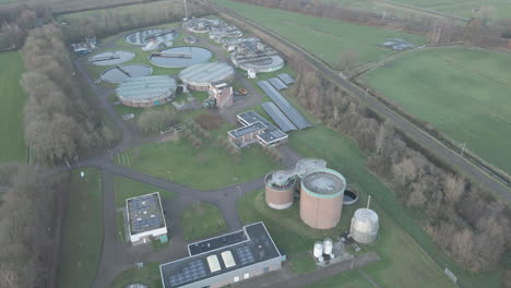 Aerial-of-small-sewage-water-treatment-plant-in-a-rural-area-surrounded-by-green-meadows