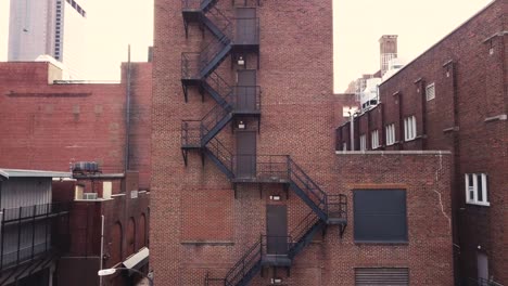 Fire-escape-ladder-and-stairs-on-the-outside-of-a-brick-building-downtown-in-the-city