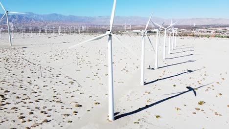 Many-windmills-rotating-in-hot-desert-area,-drone-fly-backward-shot