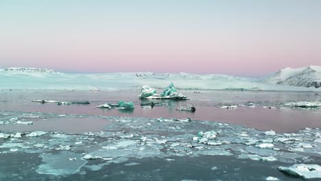 Cracked-Ice-And-Icebergs-In-Jokulsarlon-Glacial-Lake-With-Pink-Sky-At-Sunrise-In-Iceland