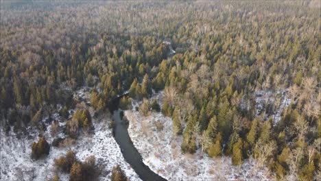 Luftaufnahme-Einer-Atemberaubenden-Winterwaldszene-Mit-Fluss,-Schnee-Und-Eis-Bei-Sonnenuntergang