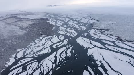 Slow-aerial-flight-over-glacial-river-delta-in-Iceland-during-foggy-and-cloudy-day-in-winter---Snowy-landscape-with-Eldvatn-River