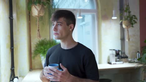 Junger-Europäischer-Männlicher-Student-Genießt-Seinen-Kaffee-Oder-Tee-Im-Kaffeehaus-Mit-Natürlichem-Hintergrund