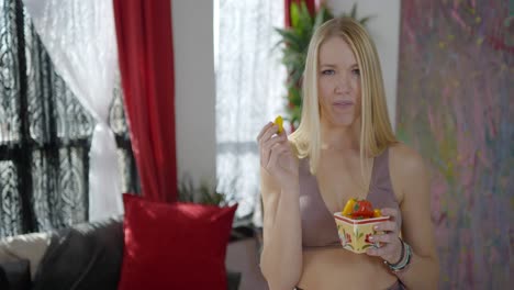 Beautiful-blonde-caucasian-white-women-girl-in-fitness-clothes-as-social-media-influencer-posing-with-and-eating-orange-and-red-peppers-promoting-healthy-eating-and-lifestyle-on-YouTube-and-TikTok