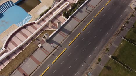 Aerial-top-down-shot-of-man-walking-on-Sidewalk-next-to-road-in-Mar-del-Plata,Argentina