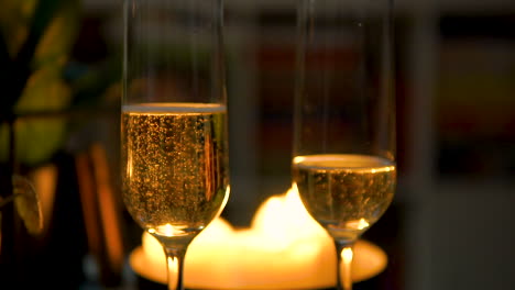 Halbgefüllte-Gläser-Mit-Prickelndem-Champagner-Am-Esstisch-Bei-Kerzenschein