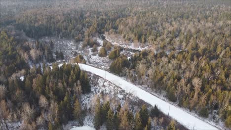 Aerial-Shot-Of-Snow-Covered-Road-Surrounded-By-Boreal-Forest-Landscape