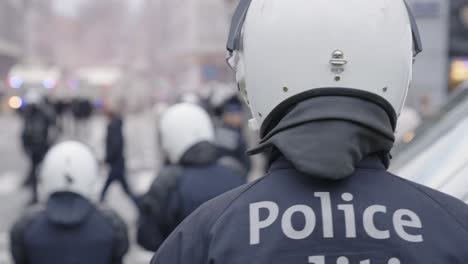 Unrecognizable-riot-police-protecting-the-city---view-from-behind-back-of-cop,-blurred-background