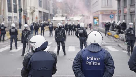 Belgian-police-line-both-sides-of-the-street-in-full-riot-gear-during-protest,-slow-motion