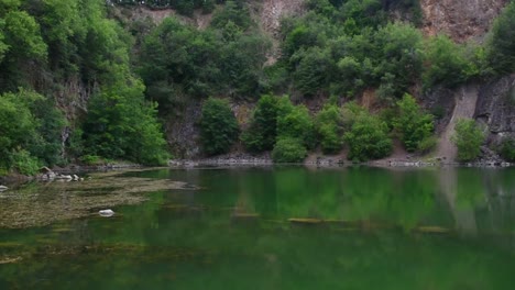 Static-view-of-beautiful-green-lake-with-clear-water-and-erosion-rock-formation-in-background,-summer-day
