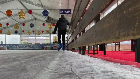 Kleines-Mädchen,-Das-Allein-Auf-Eis-In-Einer-Leeren-Indoor-Eisbahn-Mit-Weihnachtsdekorationen-Eisläuft
