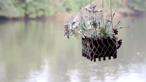 A-decorative-flower-pot-hanging-from-a-house-boat-floating-on-a-river,-a-natural-setting-embracing-the-beauty-of-nature-in-Kanchanaburi,-Thailand