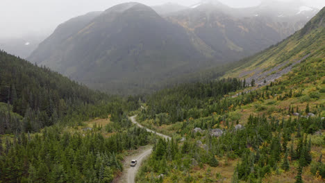 Wide-aerial-of-truck-driving-dirt-road-through-British-Columbia-mountains