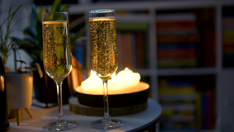 Gläser-Champagner-Mit-Blasen-Auf-Dem-Tisch-Mit-Kerzenbeleuchtetem-Hintergrund