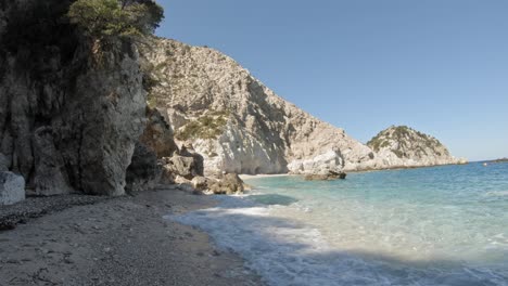 Clear-waves-rolling-over-the-rocky-beach-by-the-mountain-shoreline-of-Kefalonia