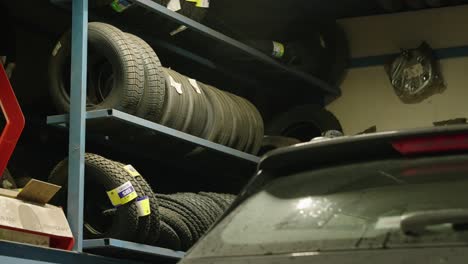 Close-up-of-a-garage-with-stacked-tires-and-car