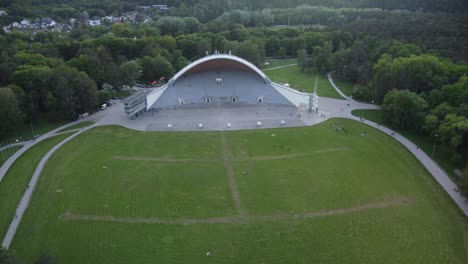 White-amphitheater-building-surrounded-by-green-forest-park-in-Vilnius,-Lithuania