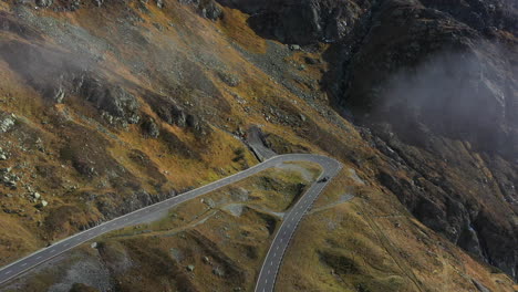 Descending-drone-footage-of-the-Susten-Pass-in-the-Swiss-Alps-in-Switzerland-with-a-vehicle-driving-on-the-road