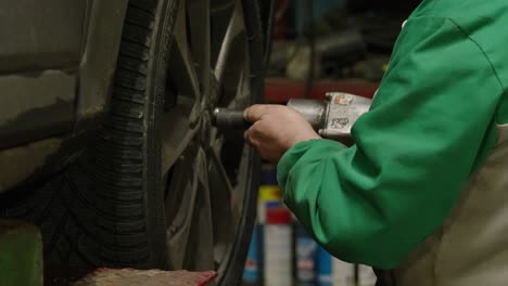 Close-up-of-mechanic's-hands-screwing-a-wheel-with-an-automatic-screwdriver