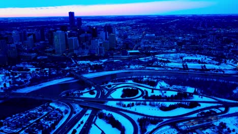 Winter-Innenstadt-Von-Edmonton-Sonnenuntergang-Rückflug-Schwenk-Aus-Der-Innenstadt-Ostseite-über-Den-Rand-Des-Flusses-Klassische-Ikonische-Low-Level--Und-James-MacDonald-Brücken-Mit-Schneebedeckter-Riverdale-Gemeinde-1-2