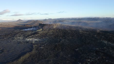 Toma-Aérea-Hacia-Atrás-Del-Cráter-Del-Volcán-En-Ebullición-Durante-La-Luz-Del-Sol-Y-El-Cielo-Azul---Geldingadalir,islandia