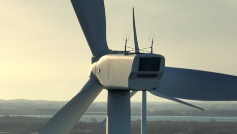 Aerial-closeup-shot-of-the-back-of-rotating-blades-on-a-wind-turbine-at-sunset-on-a-sunny-day