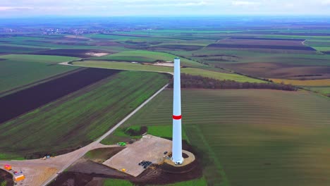 Construction-Of-Wind-Turbine-Tower-In-Farm-Field---aerial-drone-shot