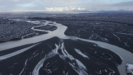 Aerial-flyover-Glacial-River-named-Sula-flowing-between-black-volcanic-landscape-in-Iceland